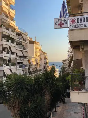 a city street with buildings and palm trees and a sign at Hidden gem on the Piraeus Coast in Piraeus