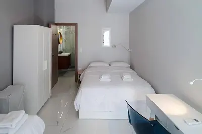a white bedroom with a large bed and a desk at Hidden gem on the Piraeus Coast in Piraeus
