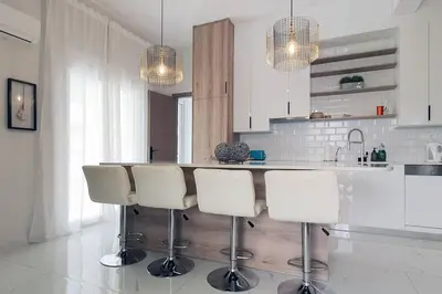 a kitchen with a bar with white chairs in it at Hidden gem on the Piraeus Coast in Piraeus