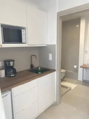 a white kitchen with a sink and a microwave at Serafina suite byArtistUnknown in Vari