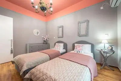 two beds in a room with pink and gray walls at Rest sleep repeat by museum in a modern Victorian way in Athens