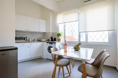 a kitchen with white cabinets and a table and chairs at Best spot apartment in Athens in Athens