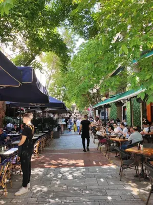a group of people sitting at tables in an outdoor restaurant at Best spot apartment in Athens in Athens