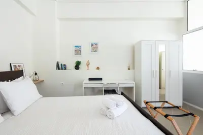 a white bedroom with a bed and a desk at Best spot apartment in Athens in Athens