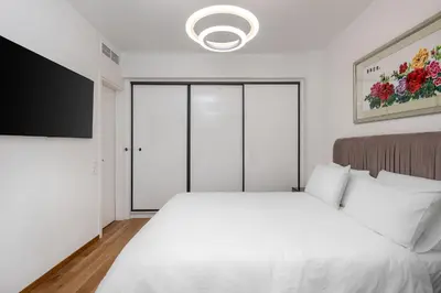 a bedroom with a white bed and a flat screen tv at Athens Riviera Penthouse in Athens