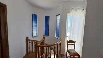 a room with a staircase and windows with blue shutters at Amazing villa with a magic view to the Aegean in Dhaskalión