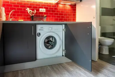 a washing machine in a bathroom with a red brick wall at Studio Apartment next to Alsos Ilision in Athens