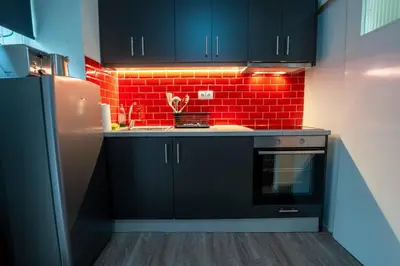 a kitchen with black cabinets and a red brick wall at Studio Apartment next to Alsos Ilision in Athens