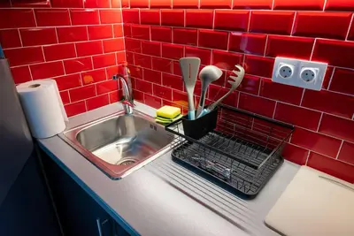 a kitchen counter with a sink and a red tile wall at Studio Apartment next to Alsos Ilision in Athens