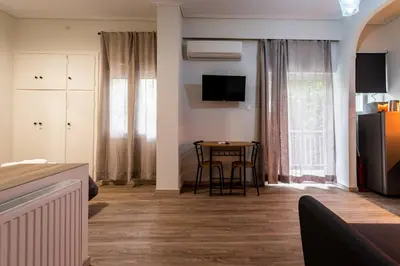 a living room with a table and a television on the wall at Studio Apartment next to Alsos Ilision in Athens