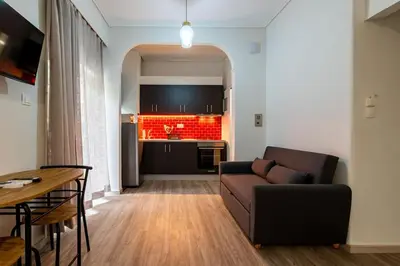a living room with a couch and a kitchen at Studio Apartment next to Alsos Ilision in Athens