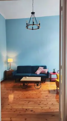 a living room with a blue couch and a table at Yellow and blue relax house in Piraeus
