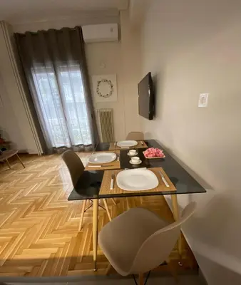 a dining room with a table and chairs and a television at Nike’s Katechaki in Athens