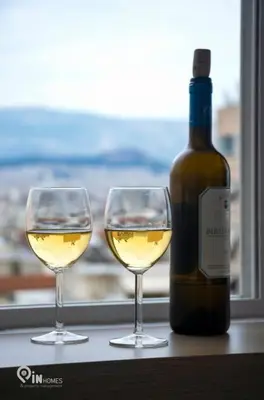 two glasses of white wine next to a bottle of wine at Athenian Sky View - next to Metro in Athens