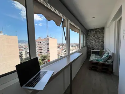 a laptop sitting on a desk in a room with windows at Athenian Sky View - next to Metro in Athens