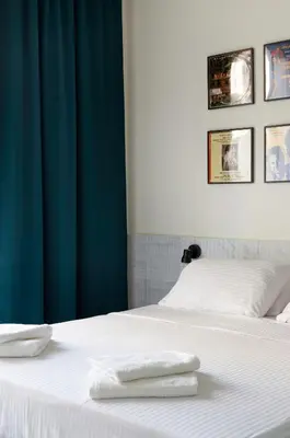 a bed with white sheets and a blue curtain at Mooeve Exarchia in Athens