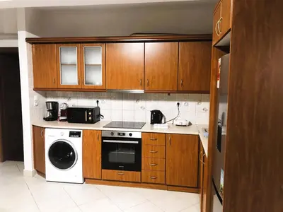 a kitchen with wooden cabinets and a washer and dryer at Cozy 2 bedroom apartment in Piraeus in Piraeus