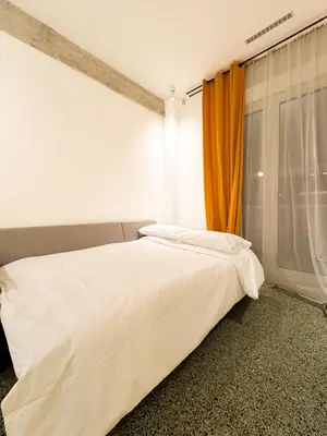 a white bed in a room with an orange curtain at Nueva era @ Athens heart , Romvis apartments in Athens