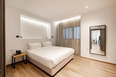 a white bedroom with a large bed and a mirror at Pnoe Urban Living in Athens