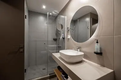 a bathroom with a sink and a shower with a mirror at Pnoe Urban Living in Athens
