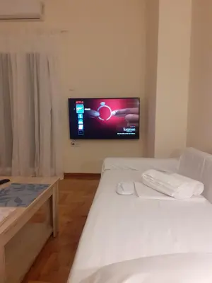 a room with two beds and a tv on the wall at A Apartments in Athens