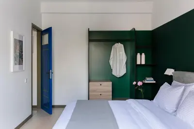 a bedroom with a white bed and a green wall at Nileos House in Athens