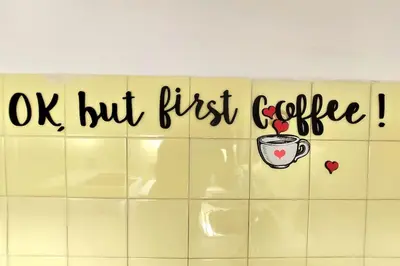 a tiled wall with a sign that says ok but first coffee at Your Perfect Place 1min from Kato Patissia Station -100Mbps in Athens