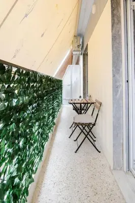 a table and chairs on a balcony with a green wall at Your Perfect Place 1min from Kato Patissia Station -100Mbps in Athens