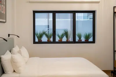 a bedroom with a bed and a window with potted plants at Earos Urban Living in Athens