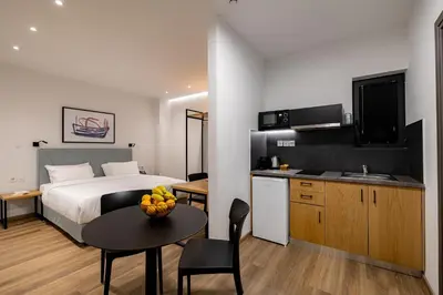 a bedroom with a bed and a table and a kitchen at Earos Urban Living in Athens