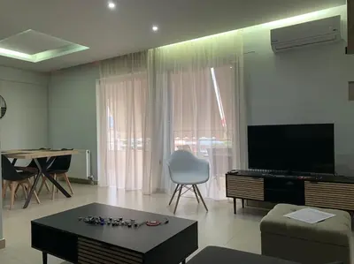 a living room with a couch and a table and a television at Varkiza Lux Apartment in Varkiza