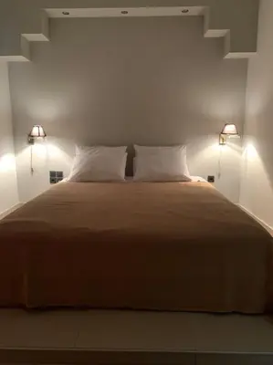 a bedroom with a large bed with two lights at Varkiza Lux Apartment in Varkiza