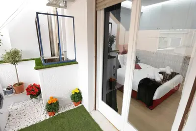 a room with a balcony with a bed and a window at Penthouse in the Heart of Athens in Athens
