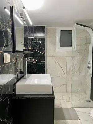 a bathroom with a white sink and a shower at Emerald Luxury Apartments - ATH Airport in Spáta