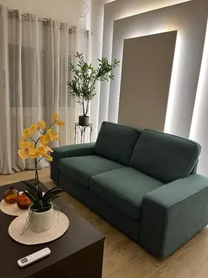 a living room with a green couch and a table at Emerald Luxury Apartments - ATH Airport in Spáta