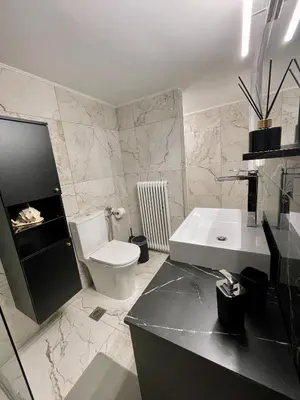 a bathroom with a white toilet and a sink at Emerald Luxury Apartments - ATH Airport in Spáta