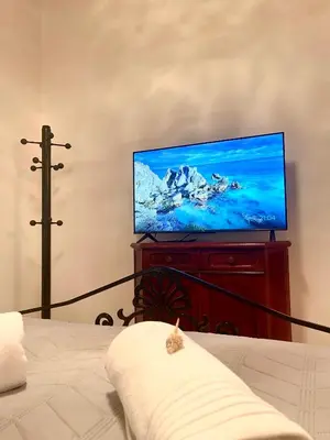 a living room with a flat screen tv on a dresser at Emerald Luxury Apartments - ATH Airport in Spáta