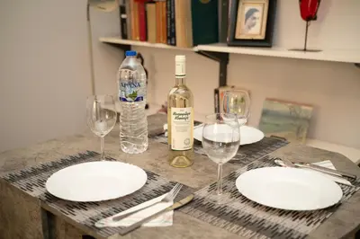 a table with white plates and a bottle of wine at Angel Apartment in Athens
