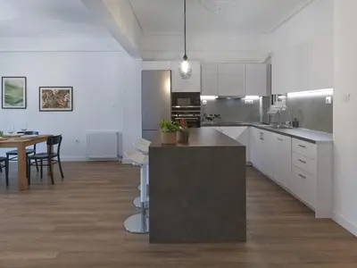 a kitchen with white cabinets and a table in it at Aiginitou6 in Athens