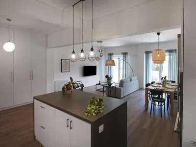 a kitchen and living room with white cabinets and a table at Aiginitou6 in Athens