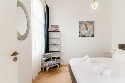 a bedroom with a bed and a mirror and a chair at Neoclassical Loft in Monastiraki - Acropolis and metro in Athens