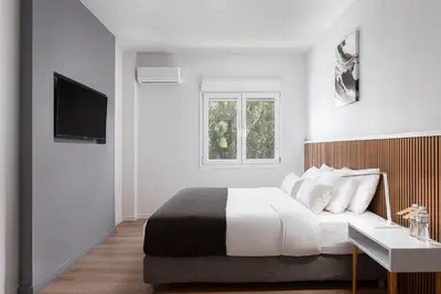 a white bedroom with a bed and a window at Acropolis Sherlock Residence in Athens