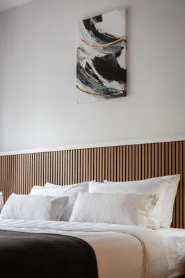 a bed with white pillows and a painting on the wall at Acropolis Sherlock Residence in Athens
