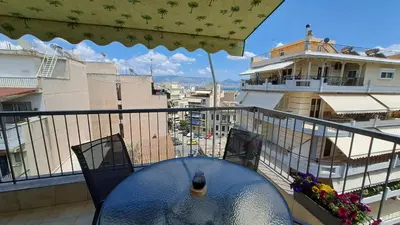 a table on a balcony with a view of a building at Tomis Sea View Apartment in Piraeus