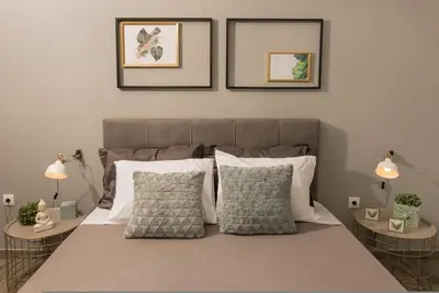 a bedroom with a bed with pillows and two tables at Our Cosy home - AT001 in Athens