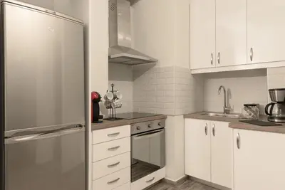 a kitchen with white cabinets and a stainless steel refrigerator at Our Cosy home - AT001 in Athens