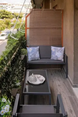a patio with a couch and a table on a balcony at Our Cosy home - AT001 in Athens