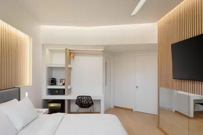a bedroom with a bed and a desk and a tv at Kreoli Hotel in Athens