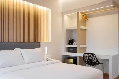 a bedroom with a white bed and a black chair at Kreoli Hotel in Athens
