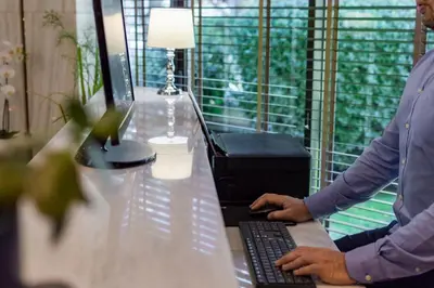 a man is typing on a computer on a desk at Acropol Hotel in Athens